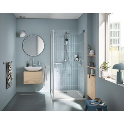 Grohe Vitalio START System 250 installeret i et moderne, lyseblåt badeværelse med glasbrusevæg og vandbesparende funktion.