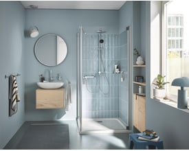 Grohe Vitalio START System 250 installeret i et moderne, lyseblåt badeværelse med glasbrusevæg og vandbesparende funktion.
