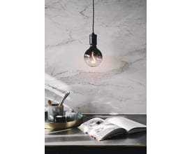 Halo Design COLORS Soft Light LED G125 lampe med røgfarvet glas hænger over et bord med en åben bog og dekorative elementer.