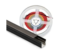 Nærbillede af en sort aluminiumsprofil til LED lys og en rullet LED strip på en metalspole, isoleret på hvid baggrund.