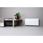 Adax Clea WiFi el-radiator monteret på væg i et stilfuldt rum med en bænk og dekoration, viser dens integration i interiøret.