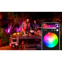 En havefest med Philips Hue Lily spots, der lyser med forskellige farver, og en smartphone viser Hue app styring.