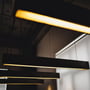 V-TAC 40 W LED-takarmatur i svart lyser varmt i et mørkt rom sammen med flere lignende pendellamper.