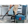 Bosch GAS 18V-10L Professional-støvsuger står på gulvet mens en person støvsuger i et lyst verksted.