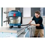 Bosch GAS 18V-10L Professional-støvsuger står på en arbeidsbenk mens en håndverker støvsuger ved kanten av benken.