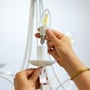 Nærbillede af en hånd, der monterer en WiZ LED kertepære i en hvid lampeholder.