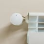 Shelly BLU TRV Gen3 radiatortermostat montert på en radiator, sett rett forfra med displayet slått på.