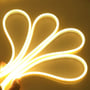 En hånd holder en lysende LEDlife Neon Flex LED-strip i en varm hvid farve, der former sig fleksibelt.