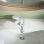 Grohe Swift et-grebs armatur installeret på et hvidt håndvask, fremviser den elegante kromfinish. Et-grebs betjeningen er vist i brug med den integrerede løft-op stang og betjeningsindikatorer.
